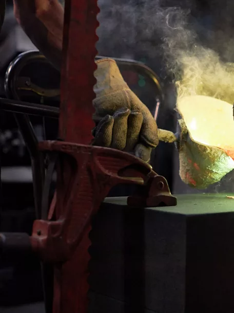 A manufacturing facility where molten metal is being poured into a mold for the brass part of the Rock.01 sink.